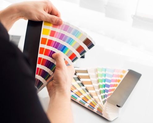 A person looking through a color swatch booklet to find the right color for their brand.